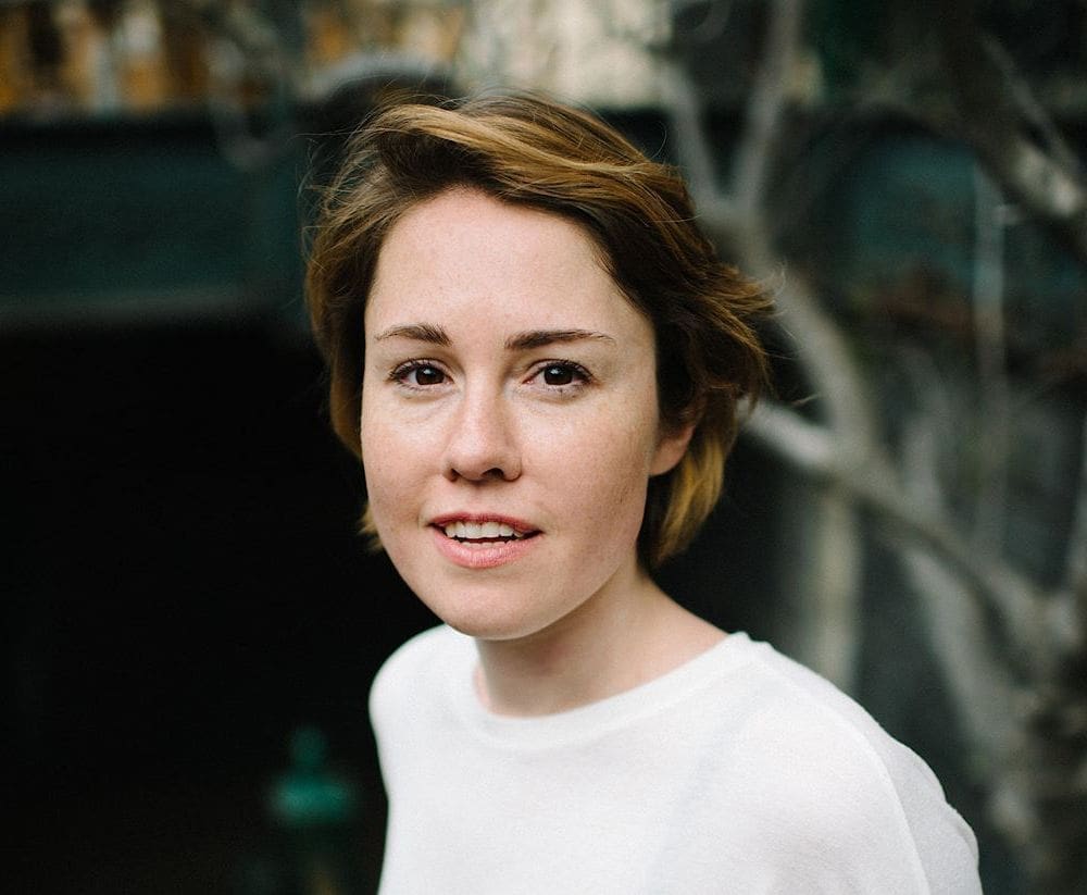 A woman wearing a white top poses for a headshot