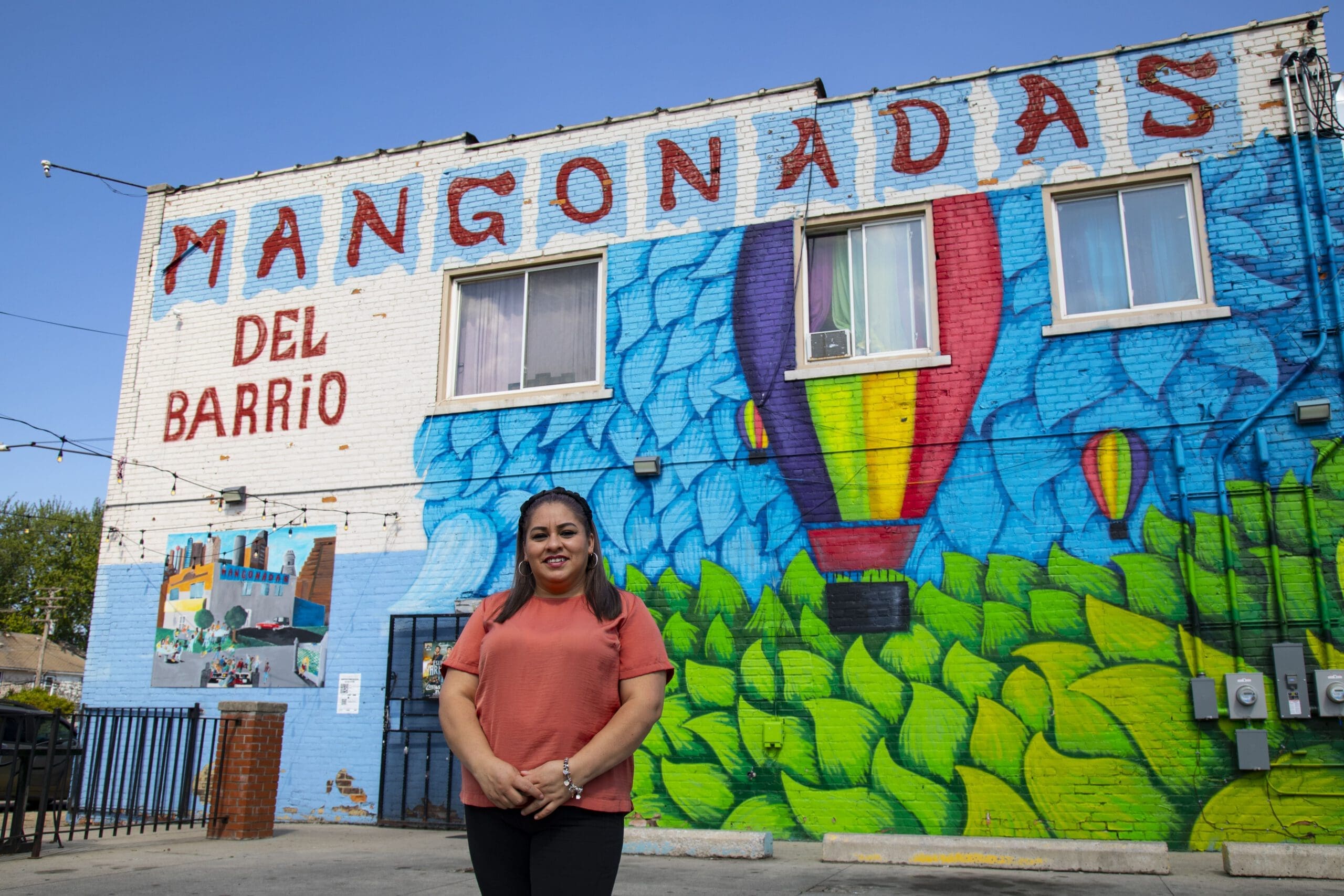 A woman poses with her hands clasped in front of her and smiles for a photograph