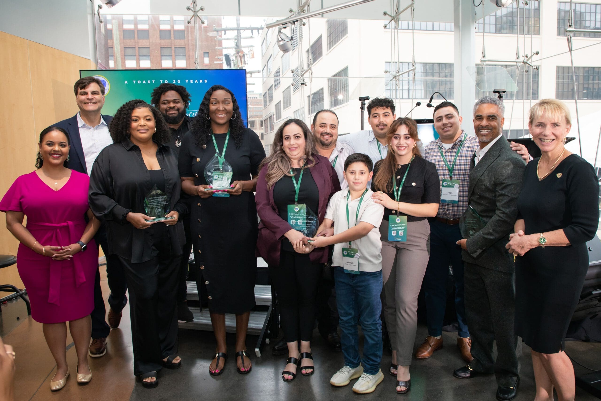 A group of people smiling for a photograph. Several of them are holding up Salute Award trophies from TechTown Detroit