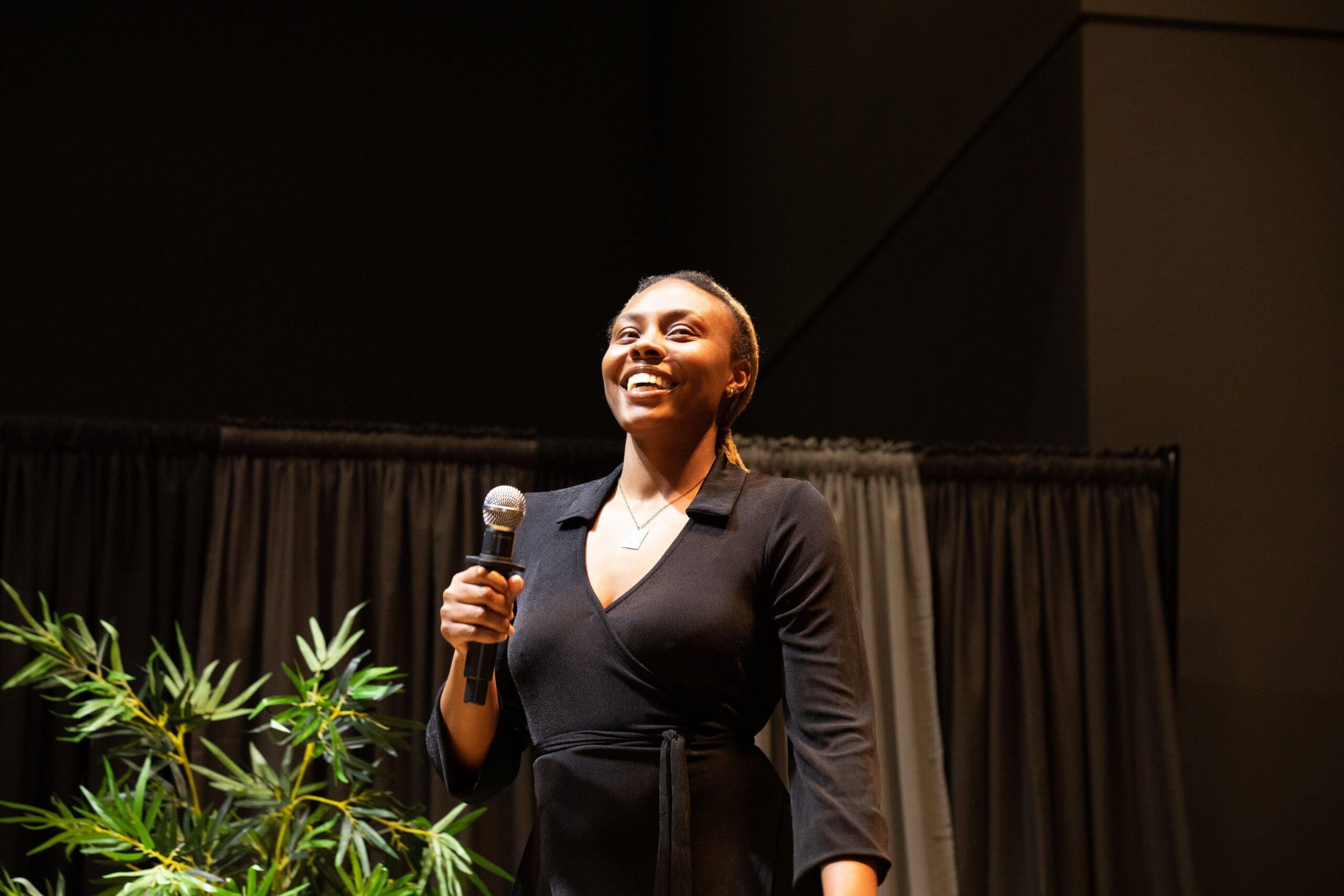 A woman smiles as she holds a microphone.